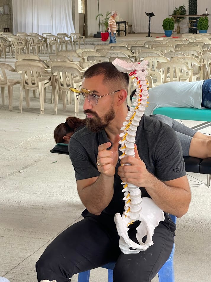 Dr. Kevin explicando anatomía de columna con modelo didáctico en misión comunitaria
